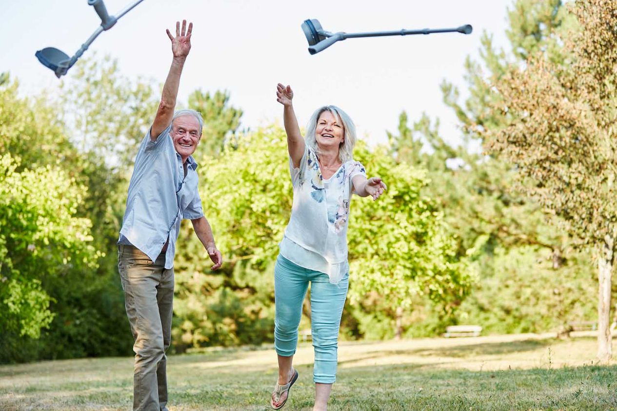 Seniorenpaar in Natur wirft Krücken weg